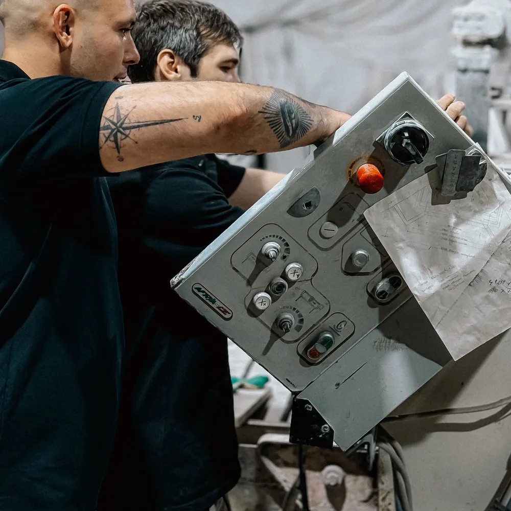 Technicians working at the control panel of an industrial machine